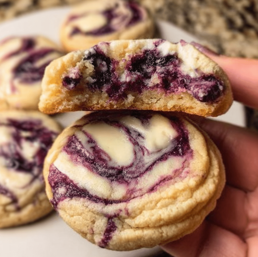 Blueberry cheesecake swirl cookies with cream cheese filling and purple blueberry swirl on parchment paper