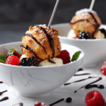 Deep fried marshmallows served with vanilla ice cream, berries, and chocolate sauce