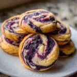Blueberry cheesecake swirl cookies with cream cheese filling and purple blueberry swirl on parchment paper