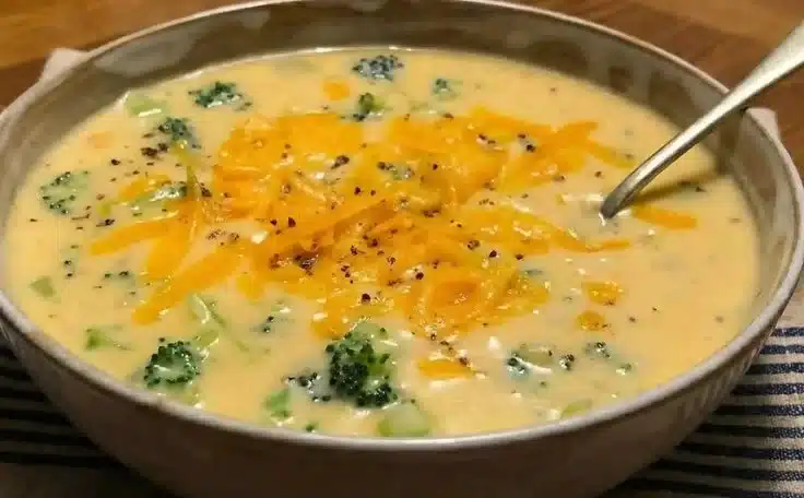 Bowl of creamy broccoli cheddar soup topped with shredded cheese and croutons