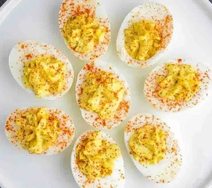 Classic deviled eggs arranged on a platter, garnished with paprika and herbs